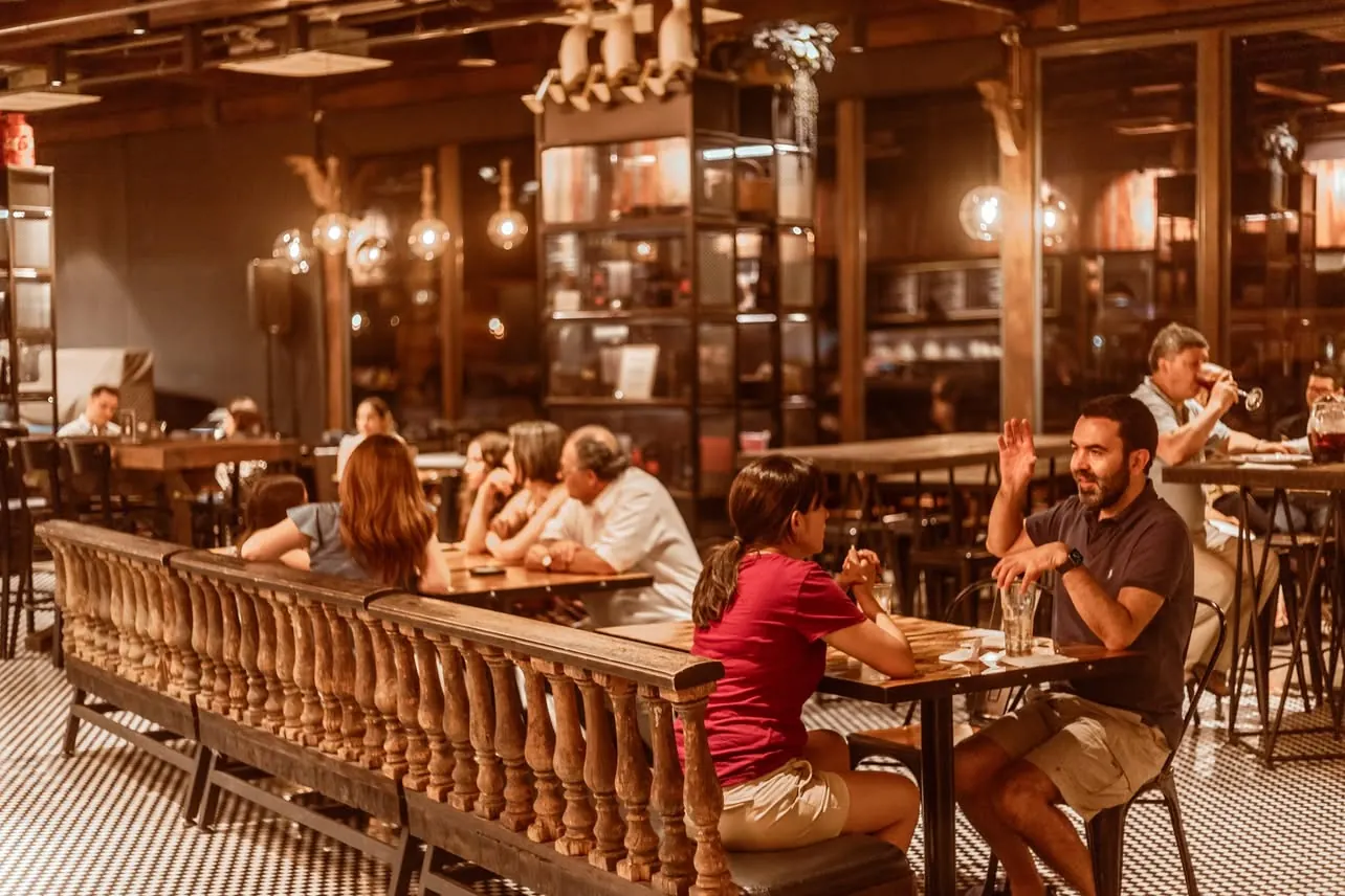 Salón de Tentadero con barandas de madera y mesas compartidas